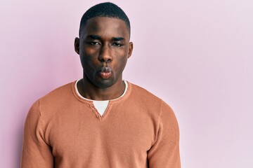 Obraz premium Young african american man wearing casual clothes making fish face with lips, crazy and comical gesture. funny expression.