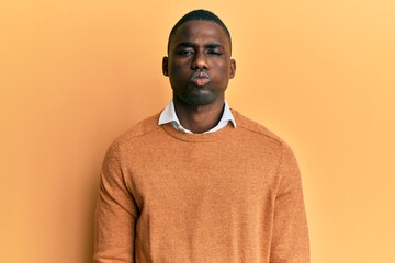 Fototapeta premium Young african american man wearing casual clothes puffing cheeks with funny face. mouth inflated with air, crazy expression.