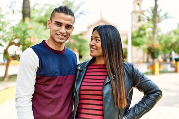 Obraz premium Young latin couple smiling happy and hugging walking at the street of city.