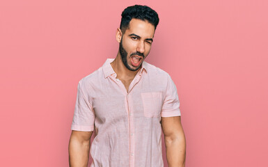 Hispanic man with beard wearing casual shirt winking looking at the camera with sexy expression,...