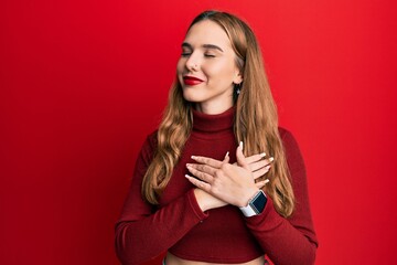 Fototapeta premium Young blonde woman wearing turtleneck sweater smiling with hands on chest with closed eyes and grateful gesture on face. health concept.