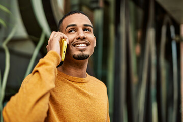 Young african american man smiling happy talking on the smartphone at the city.
