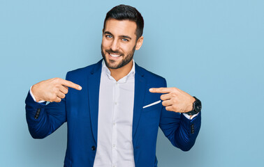 Young hispanic man wearing business jacket looking confident with smile on face, pointing oneself...