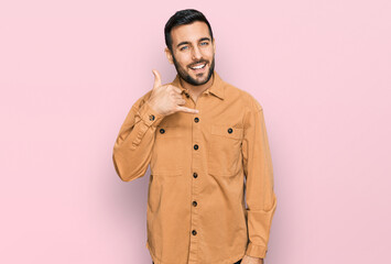 Young hispanic man wearing casual clothes smiling doing phone gesture with hand and fingers like talking on the telephone. communicating concepts.