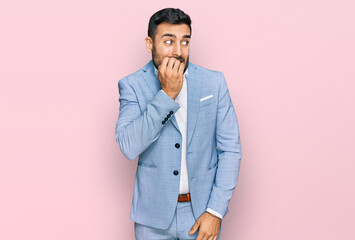 Young hispanic man wearing business jacket looking stressed and nervous with hands on mouth biting nails. anxiety problem.