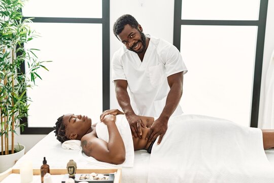 Young physiotherapist man giving abdominal massage to african american woman at the clinic