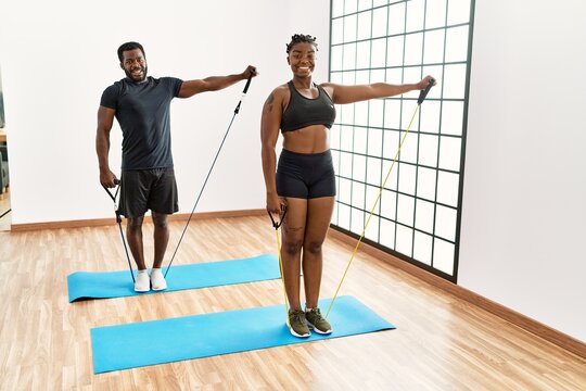 Young african american couple smiling happy training using elastic bands at home.