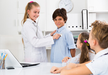 Fototapeta premium Medic girl with stethoscope with patient boy in the doctor's office