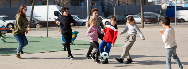 Company of glad children playing football on the street. High quality photo