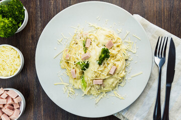 Delicious Fettuccine with white sauce, broccoli, turkey breast cubes and grated cheese. Selective focus. Top view.