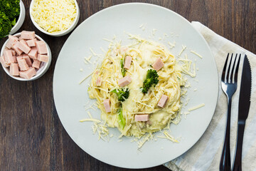 Delicious Fettuccine with white sauce, broccoli, turkey breast cubes and grated cheese. Selective focus. Top view.