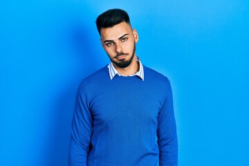 Fototapeta premium Young hispanic man with beard wearing casual blue sweater looking sleepy and tired, exhausted for fatigue and hangover, lazy eyes in the morning.