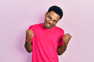 Young african american man wearing casua t shirt very happy and excited doing winner gesture with arms raised, smiling and screaming for success. celebration concept.