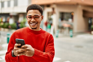 Handsome african american man outdoors using smartphone typing a message