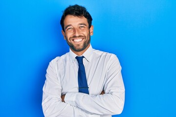 Handsome man with beard wearing business shirt and tie happy face smiling with crossed arms looking at the camera. positive person.