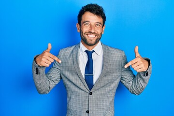 Handsome man with beard wearing business suit and tie looking confident with smile on face, pointing oneself with fingers proud and happy.