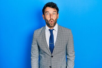 Handsome man with beard wearing business suit and tie afraid and shocked with surprise expression, fear and excited face.
