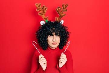 Young middle east woman wearing cute christmas reindeer horns skeptic and nervous, frowning upset because of problem. negative person.