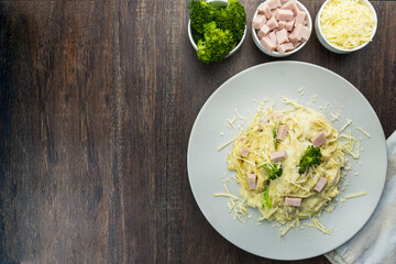 Delicious Fettuccine with white sauce, broccoli, turkey breast cubes and grated cheese. Selective focus. Top view.