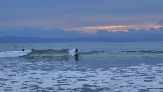 surfer in the pacific ocean pastel colors sunset Costa Rica slow motion