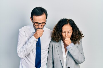 Middle age couple of hispanic woman and man wearing business office uniform feeling unwell and coughing as symptom for cold or bronchitis. health care concept.