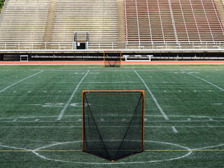 Empty Lacrosse goal nets await the start of play.  Stadium seating.
