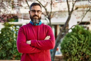 Young hispanic executive man smiling happy with arms crossed gesture at the city.