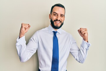 Young man with beard wearing business tie celebrating surprised and amazed for success with arms raised and open eyes. winner concept.