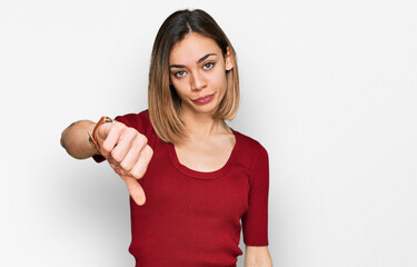 Young blonde girl wearing casual clothes looking unhappy and angry showing rejection and negative with thumbs down gesture. bad expression.