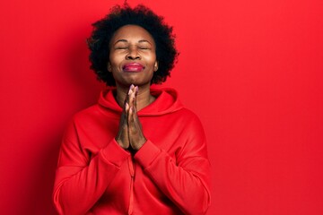 Young african american woman wearing casual sweatshirt praying with hands together asking for...