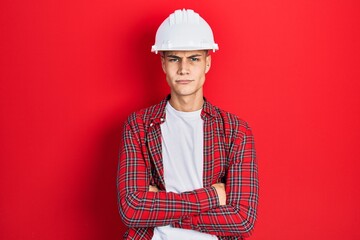 Young hispanic man wearing architect hardhat skeptic and nervous, disapproving expression on face with crossed arms. negative person.