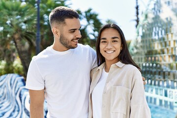 Fototapeta premium Young latin couple smiling happy and hugging at the city.