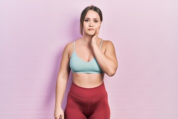 Obraz premium Young hispanic girl wearing sportswear touching mouth with hand with painful expression because of toothache or dental illness on teeth. dentist