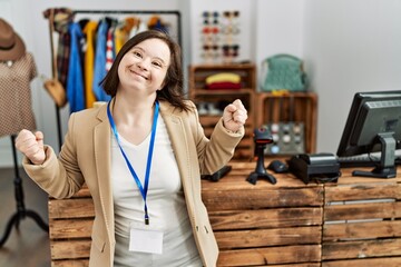 Young down syndrome woman working as manager at retail boutique very happy and excited doing winner...