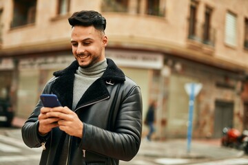 Young arab man smiling happy using smartphone at the city.