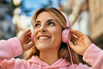 Young blonde sporty girl smiling happy using headphones at the city.