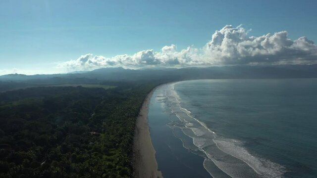 Zancudo beach Costa Rica aerial shot Pacific ocean waves on black sand beach with jungle and farmlands