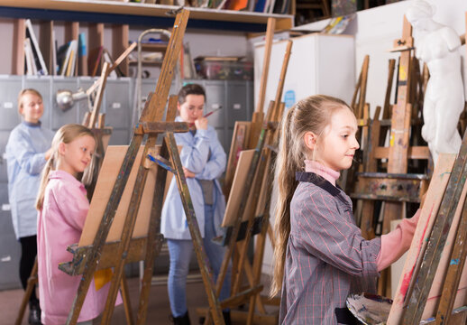 positive american schoolgirls diligently training their painting skills during class at art studio