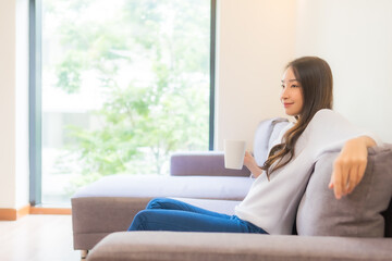 Obraz premium Portrait beautiful young asian woman with coffee cup on sofa