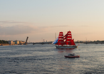 St. Petersburg, Russia, Jun 24,2021: Preparation for "Scarlet Sails" (holiday of school graduates). Red sailboat in Neva River. Trinity bridge raised in evening