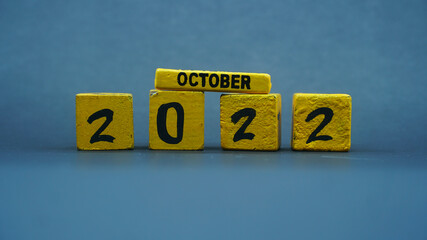 Wooden block calendar for October 2022. Yellow on a dark background