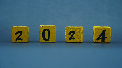 Wooden block calendar with numbers for 2024. Yellow on a dark background