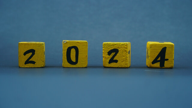 Wooden block calendar with numbers for 2024. Yellow on a dark background