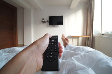 POV shot of a man using remote control for tv in hotel room.