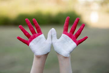 Child girl show hands painted in Indonesia and Monaco flag colors. Indonesian patriotism concept. Indonesian Independence Day, Hari Kemerdekaan Indonesia, 17 August. National Day of Monaco 19 November