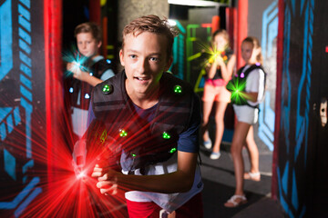 Obraz na płótnie Canvas Portrait of teenager boy with laser gun having fun on dark lasertag arena..