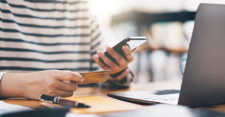 Online payment, women's hands holding a credit card and using smart phone for online shopping at home office