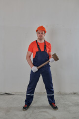 worker with a sledgehammer in his hands in an orange helmet