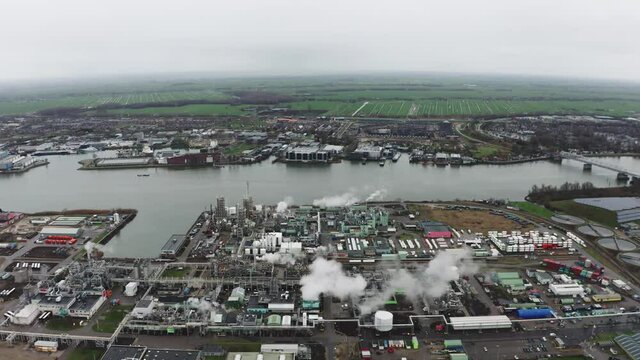 Polluted Smoke Billowing Out Of The Chimneys Of A Chemical Plant By The Riverbank. Chemours Chemical Plant In Dordrecht, Netherlands. aerial drone sideways