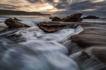 Obraz na płótnie Canvas cascades flowing into the ocean from the rocks at the beach